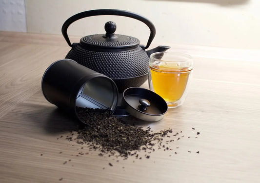 théière et du thé noir renversé d'une boîte